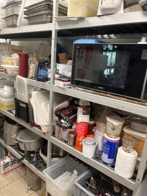 une cuisine avec beaucoup de vaisselle et un micro-ondes posé sur l'étagère