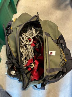 un sac de voyage rempli d'objets, posé par terre