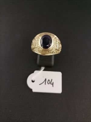a gold ring with a blue stone sits on a black surface