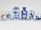 Plusieurs vases bleus et blancs sont alignés sur une surface blanche