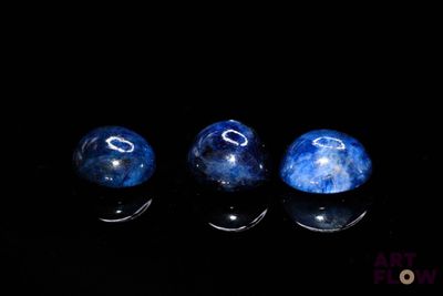 three blue marbles sitting on top of a black surface
