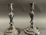 paire de bougeoirs anciens en argent posés sur un socle, sur fond gris