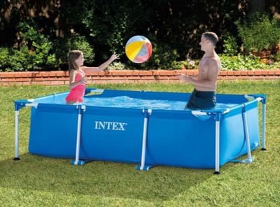deux personnes jouant avec un ballon dans une piscine installée dans l'herbe