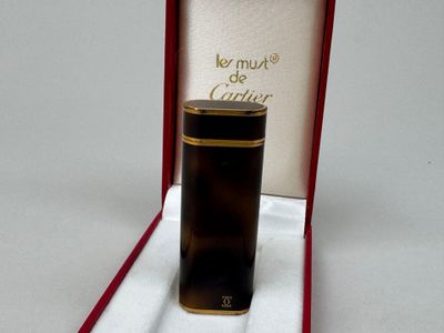 un flacon de parfum dans une boîte rouge posée sur une surface blanche, orné d'un ruban rouge