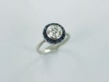 a close up of a diamond and sapphire ring on a white surface