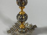 a silver and gold candle holder sitting on a table