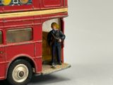 a red double decker bus with a man on the front