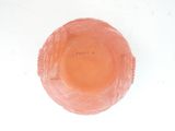 a pink glass bowl on a white surface with writing on it