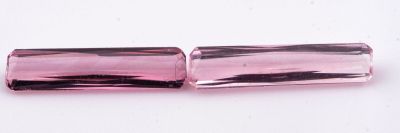 un gros plan sur deux perles de verre roses posées sur une surface blanche