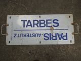 un panneau posé par terre sur lequel on peut lire « Tarbes »
