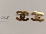 une paire de boucles d'oreilles Chanel posées sur une surface blanche