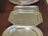 four silver trays on a long wooden table