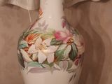 a white vase with flowers on it sitting on a table