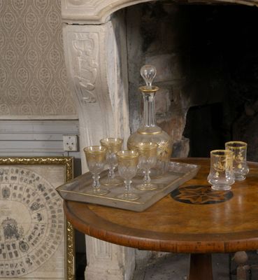 une table sur laquelle sont posés un plateau et des verres, devant une cheminée