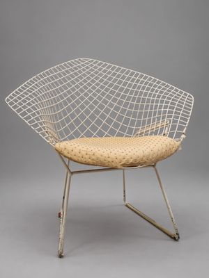 une chaise « Diamond » blanche avec une assise en osier et des pieds en métal