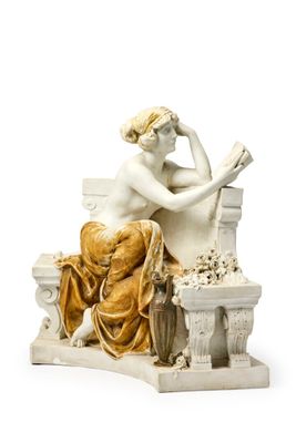 une statue représentant une femme assise sur un banc en train de lire un livre