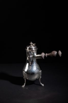 an antique silver teapot with a wooden handle on a black background