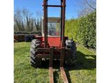 a red forklift sitting on top of a lush green field