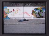 a picture of a man laying on the ground in front of a wall with graffiti