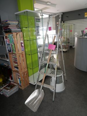 a ladder and a shovel in a room with bookshelves