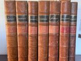 a set of five old books sitting on top of a wooden table