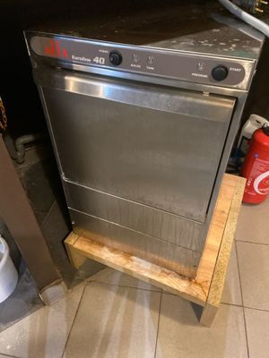 un lave-vaisselle argenté posé dans une cuisine, à côté d'une poubelle