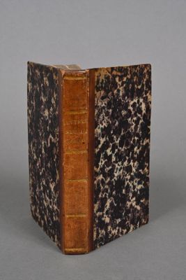 an old book sitting on top of a table next to a gray wall
