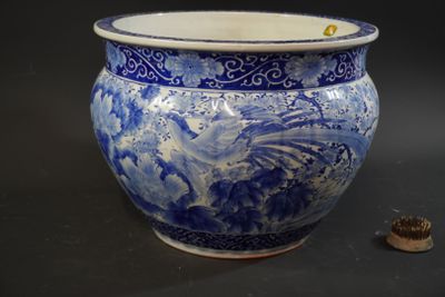 a large blue and white vase with a small coin in front of it