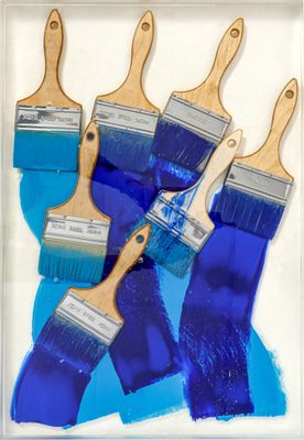 four blue paint brushes with wooden handles on a white background