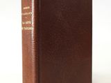 an old brown book sitting on top of a white table