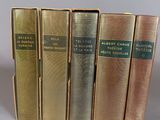 four books are lined up in a row on a gray surface
