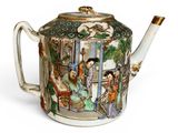 a teapot with a painting on it sitting on a table