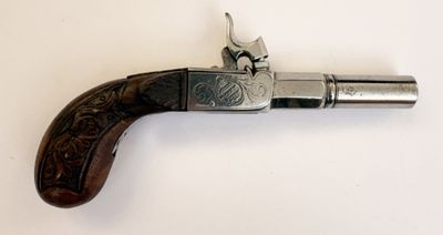 un vieux pistolet avec une poignée en bois sur une surface blanche