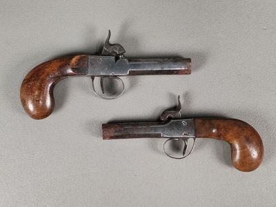 deux pistolets à crosse en bois posés sur une surface blanche