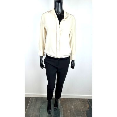 Le mannequin porte une chemise blanche et un pantalon noir.