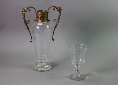 a vase and a wine glass sitting next to each other