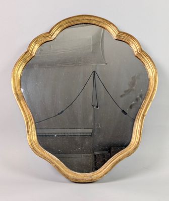 gold scallop shaped mirror on a white background with a bridge in the background