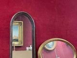 trois miroirs posés sur une étagère en bois près d'un mur rouge