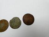 trois vieilles pièces de monnaie posées les unes à côté des autres sur une surface blanche