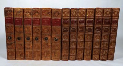 six old books are lined up in a row on a white surface