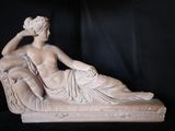 une statue représentant une femme assise sur un canapé