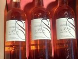 trois bouteilles de vin se trouvent dans une boîte rose posée sur une table