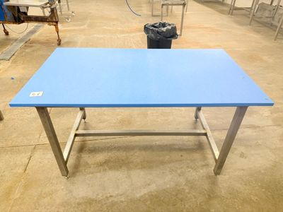 a blue table in a warehouse with chairs around it