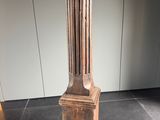 une grande colonne en bois posée à même le sol dans une pièce
