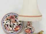 une lampe posée à côté d'une assiette décorée de fleurs