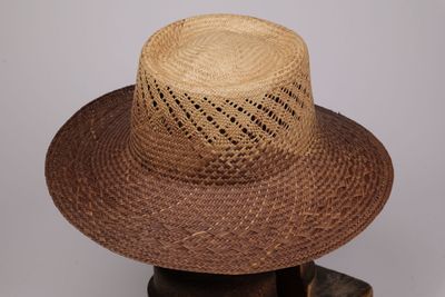 un chapeau de paille posé sur un support en bois