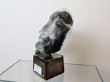 a glass table with a sculpture of a man ' s head on it