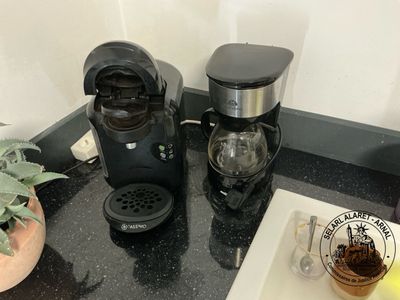 two coffee makers sitting on a counter next to a potted plant
