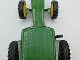 a green toy tractor that is sitting on a white surface
