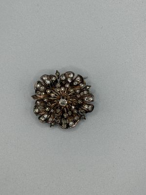 une broche en argent avec un diamant au centre, sur un fond blanc